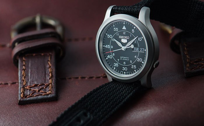 A watch resting on a brown leather bag, showcasing a stylish accessory against a rich, textured background.