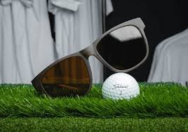 Sunglasses and a golf ball resting on green grass inside a room, creating a playful indoor golf scene.