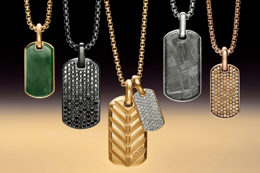Four distinct dog tags displayed on a gold chain, showcasing their unique designs and textures
